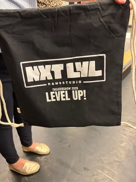 Zwarte stoffen tas met een bedrukt logo van een dansstudio en de tekst Theatershow 2026